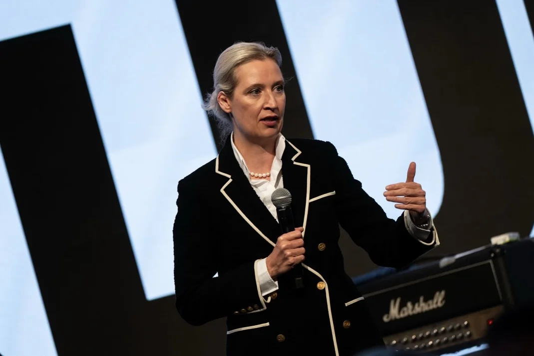 Photo by Alice Weidel on February 17, 2026. May be an image of one or more people, musical instrument, microphone, concert and text.