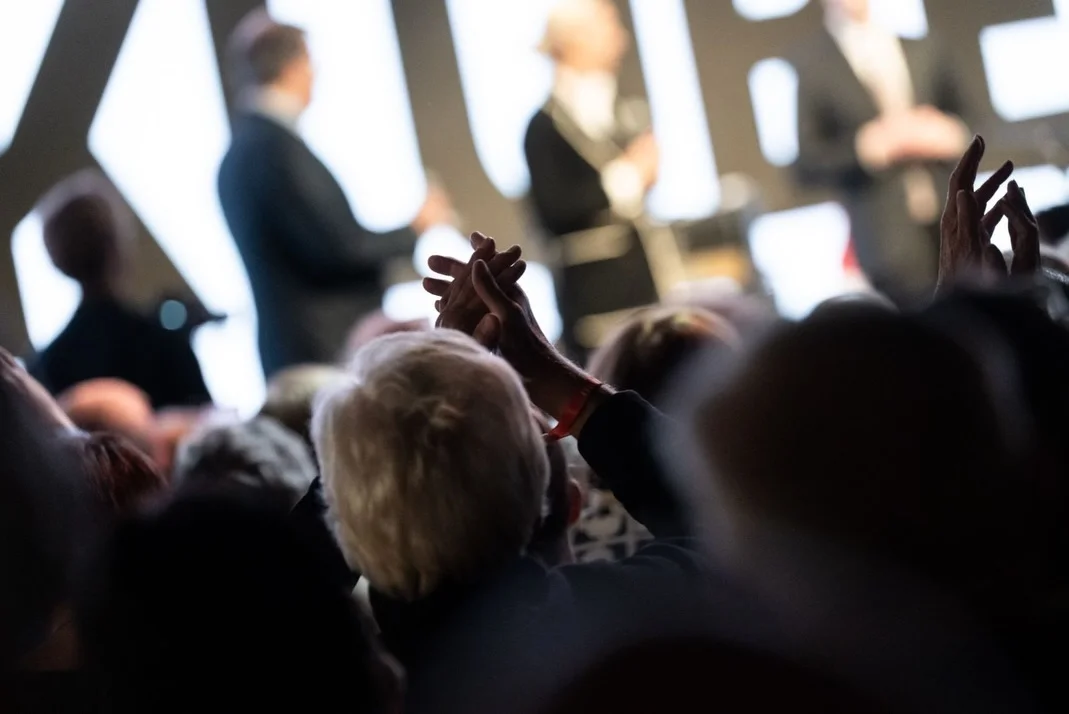 Photo by Alice Weidel on February 17, 2026. May be an image of microphone, crowd and text.