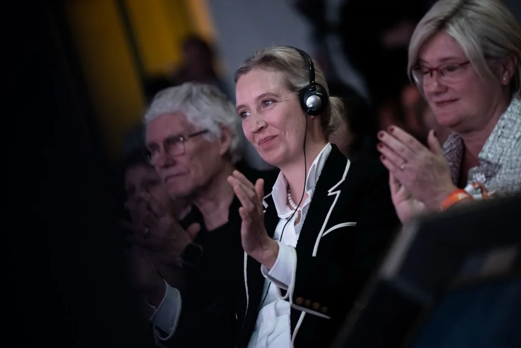 Photo by Alice Weidel on February 17, 2026. May be an image of one or more people, microphone and text.